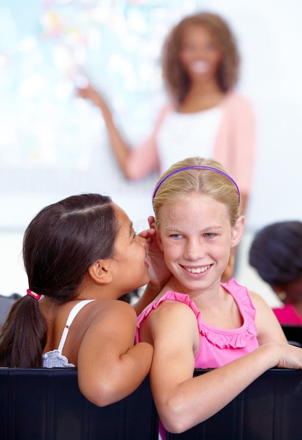 Kleine Mädchen flüstern und Klassenzimmer im Ohr für geheimes Tratsch oder Kommunikation in der Schule. Schüler stockbild