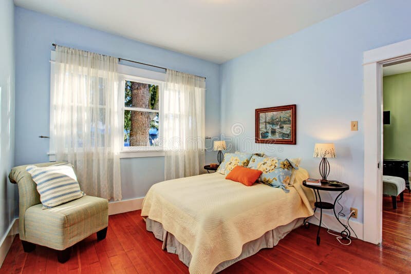 Light blue bedroom with window and hardwood floor furnished with bed and chair. Light blue bedroom with window and hardwood floor furnished with bed and chair