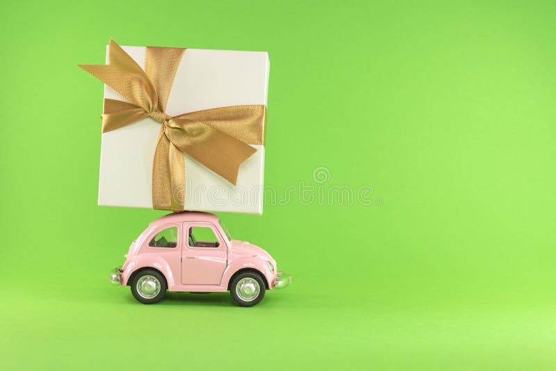 Little retro toy model car with present gift box on light green background. Christmas, birthday, valentines day, delivery concept. Vilnius, Lithuania, September 09, 2019. Little retro toy model car with present gift box on light green background. Christmas, birthday, valentines day, delivery concept. Vilnius, Lithuania, September 09, 2019.