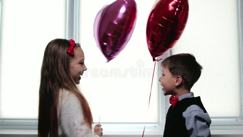 Kleine schöne Kinder Ballons mit Herzen dann Lachen und Umarmung halten und senken. Karte