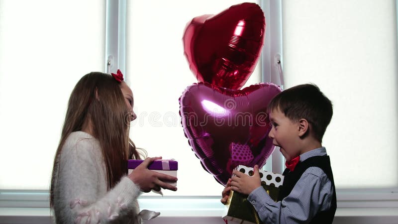 Kleine schöne Kinder mit Freude und Überraschung geben sich Geschenke. das Konzept des Valentinsgrußtages