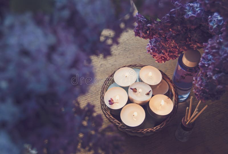 Kleine weiße Kerzen in einem Korb, in einem Massageöl und in einem Wesentlichen