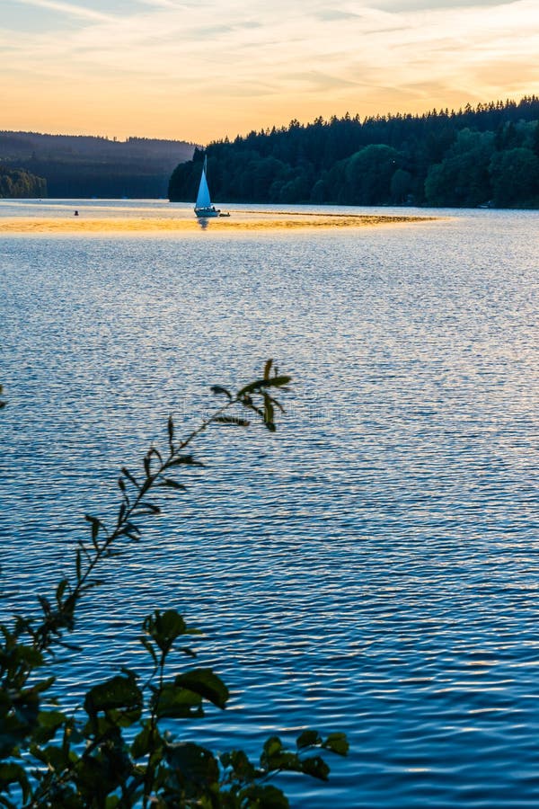 Kleine Yacht auf einem See während eines Sonnenuntergangs lizenzfreie stockfotografie Kleine Yacht auf einem See während eines Sonnenuntergangs lizenzfreie stockfotografie
