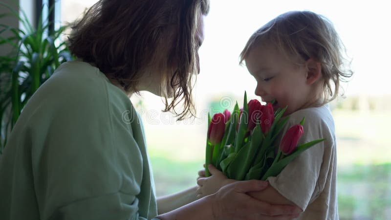 Kleine zoon geeft een mooie bloem aan zijn moeder kleine jongen bloem die een mooie verrassing maakt voor zijn moeder .