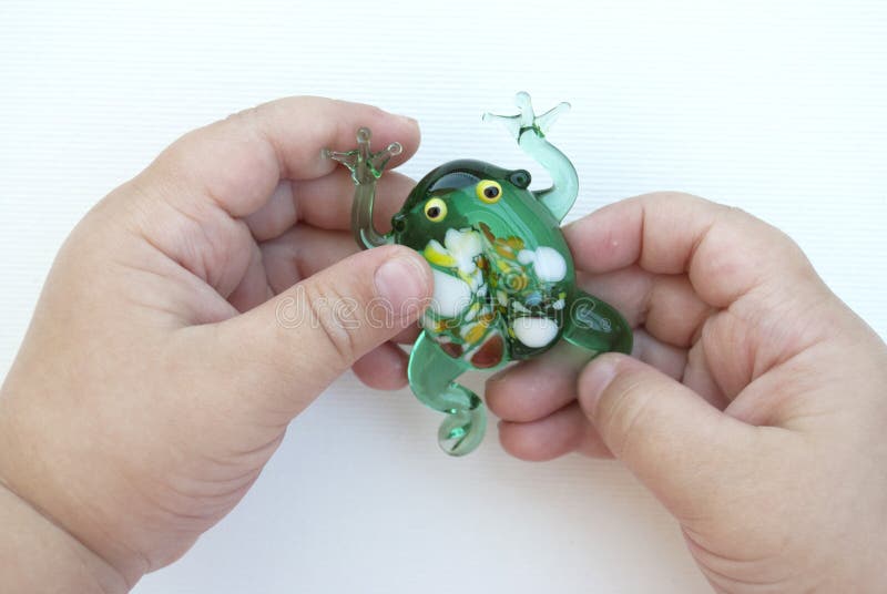 Kleiner gr?ner Frosch gemacht vom Glas in den H?nden eines Kindes auf einem wei?en Hintergrund lizenzfreies stockfoto Kleiner gr?ner Frosch gemacht vom Glas in den H?nden eines Kindes auf einem wei?en Hintergrund lizenzfreies stockfoto
