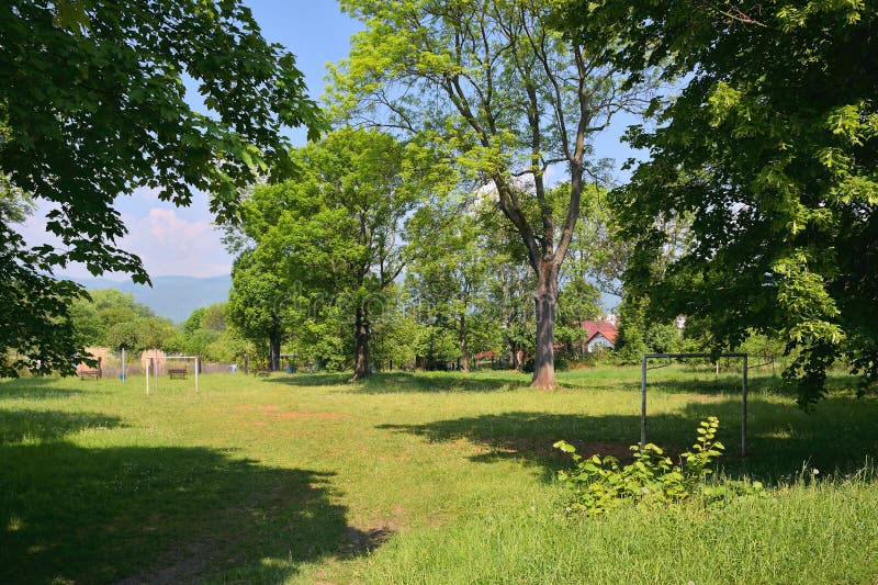 Kleiner grasartiger Fußballplatz zwischen Bäumen in der tschechischen Stadt von Chabarovice mit Erzbergen auf Hintergrund im Früh lizenzfreie stockfotos Kleiner grasartiger Fußballplatz zwischen Bäumen in der tschechischen Stadt von Chabarovice mit Erzbergen auf Hintergrund im Früh lizenzfreie stockfotos