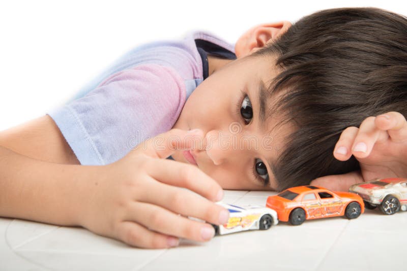 Kleiner Junge, der auf dem Tisch mit Autospielzeug allein spielt lizenzfreies stockbild Kleiner Junge, der auf dem Tisch mit Autospielzeug allein spielt lizenzfreies stockbild