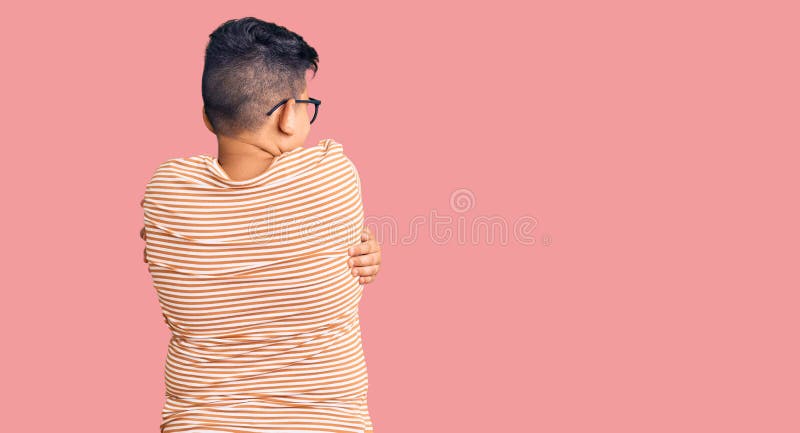 Kleiner Junge, der lockere Kleidung und Brillen trägt und sich von hinten glücklich und positiv umarmt. Selbstliebe