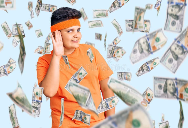 Kleiner Junge, der Sportkleidung trägt, die mit der Hand über Ohr lächelt und Gerüchten oder Tratsch lauscht stockfotografie