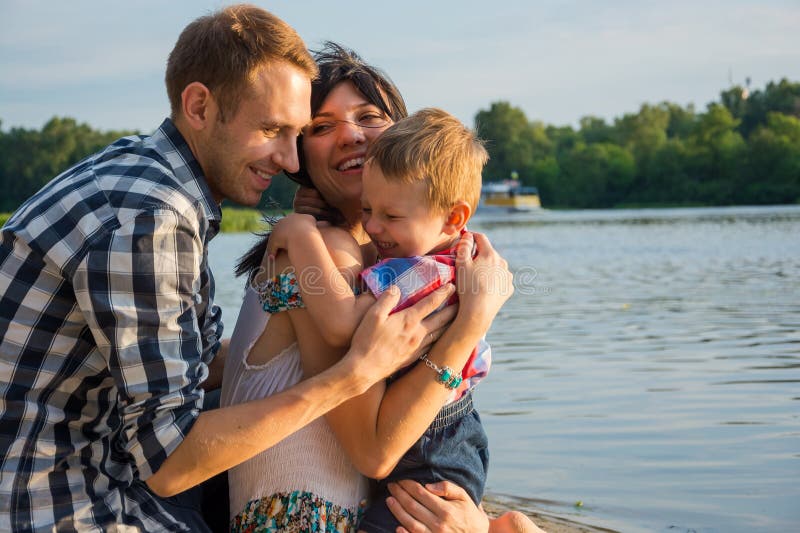 Kleiner Junge umarmt seinen Vati und Mutter und sie, die herein draußen lächeln stockfotos Kleiner Junge umarmt seinen Vati und Mutter und sie, die herein draußen lächeln stockfotos