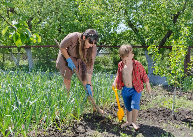 Kleiner Junge, Welche Seiner Mutter Im Garten Hilft Stockfoto Bild