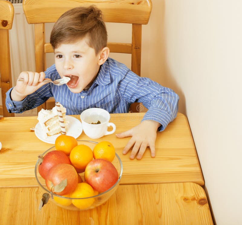 Kleiner netter Junge, der Nachtisch auf hölzerner Küche isst Wohnzimmer konzipiert in der Retro- Art lächelndes entzückendes Kind stockbilder Kleiner netter Junge, der Nachtisch auf hölzerner Küche isst Wohnzimmer konzipiert in der Retro- Art lächelndes entzückendes Kind stockbilder