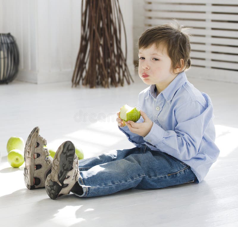 Kleiner netter Junge, der zu Hause grünen Apfel isst stockfotos Kleiner netter Junge, der zu Hause grünen Apfel isst stockfotos