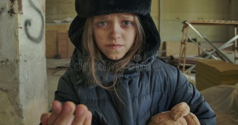 Kleiner syrischer Flüchtling in schmutzigen Winterkleidern, der um ein Aushängeschild bittet Hungriges Obdachloses Mädchen mit sc
