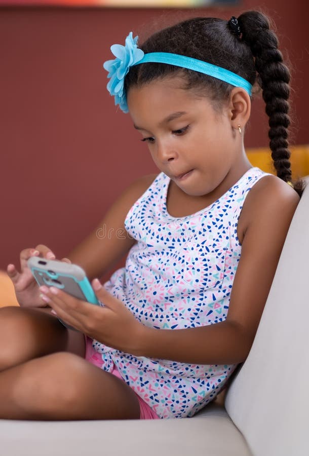 Kleines Afroamerikanermädchen, das einen Handy verwendet lizenzfreie stockfotografie Kleines Afroamerikanermädchen, das einen Handy verwendet lizenzfreie stockfotografie
