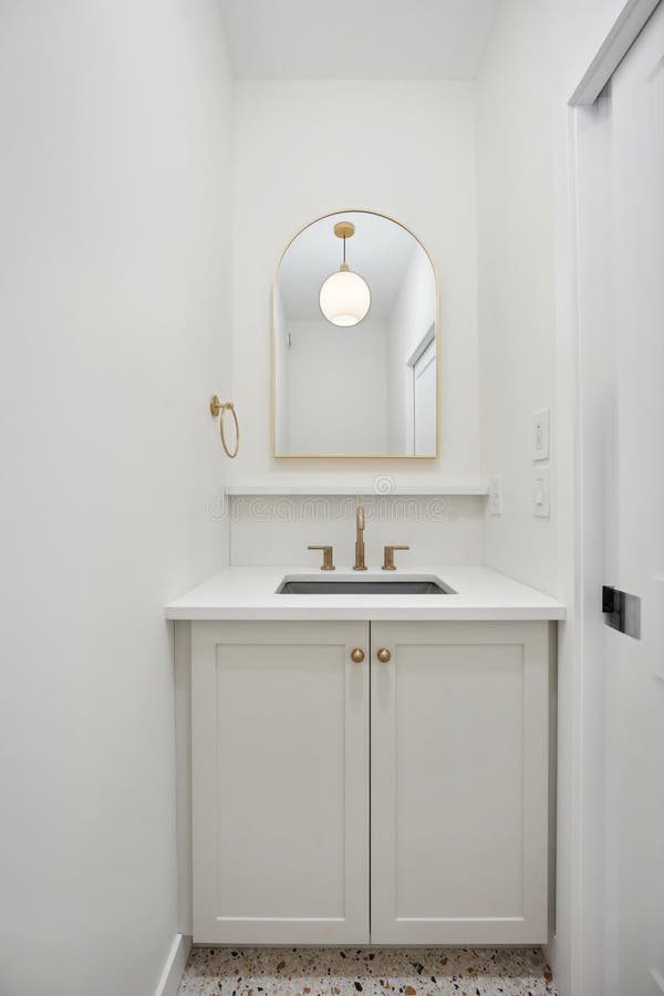 Kleines Badezimmer mit weißem Waschbecken und Goldspiegel stockbild
