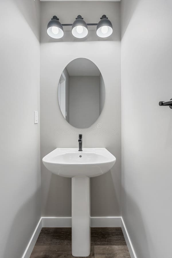 Kleines Badezimmer mit einem weißen Waschbecken und einem Spiegel stockfoto