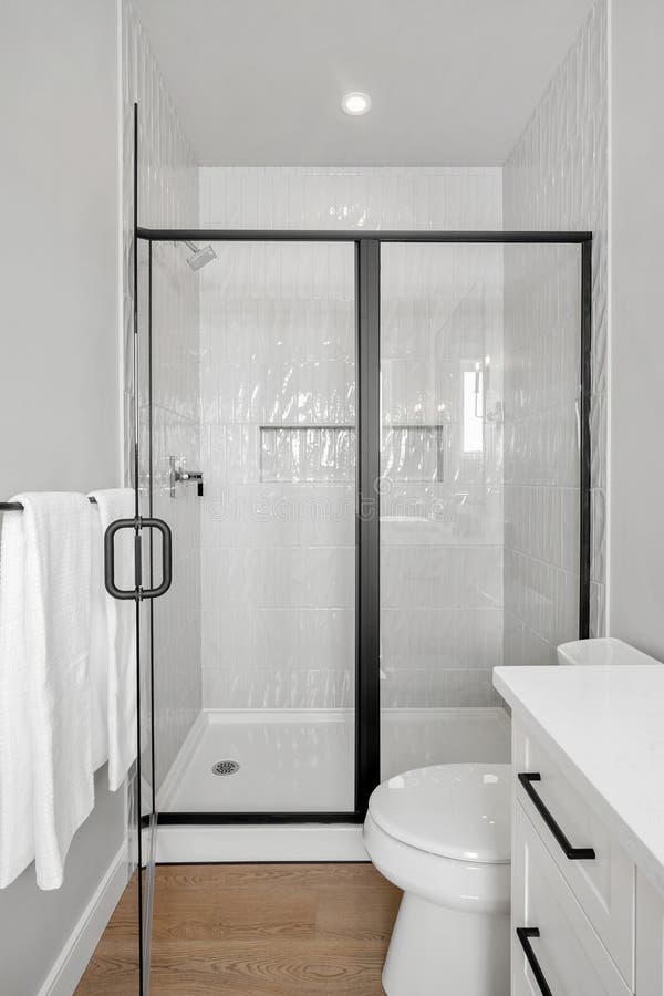 Kleines Badezimmer mit einer weißen Toilette und einer schwarzen Duschkabine stockfoto