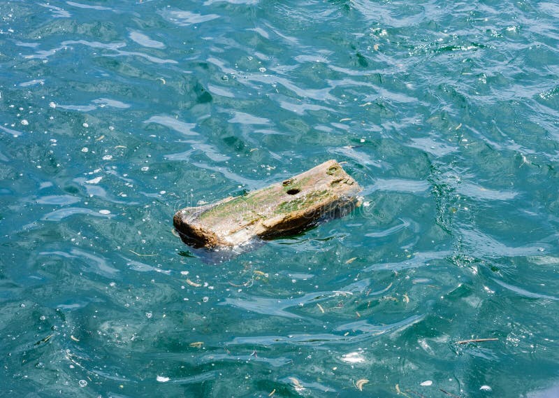 Kleines hölzernes Stück mit dem Loch, das im Wasser treibt stockfoto Kleines hölzernes Stück mit dem Loch, das im Wasser treibt stockfoto