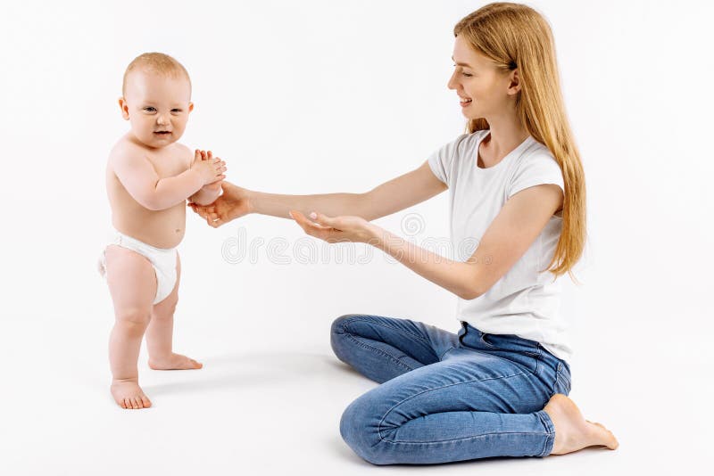 Kleines Kind lernt, mithilfe der Mutter auf einem weißen Hintergrund zu gehen. lizenzfreies stockfoto