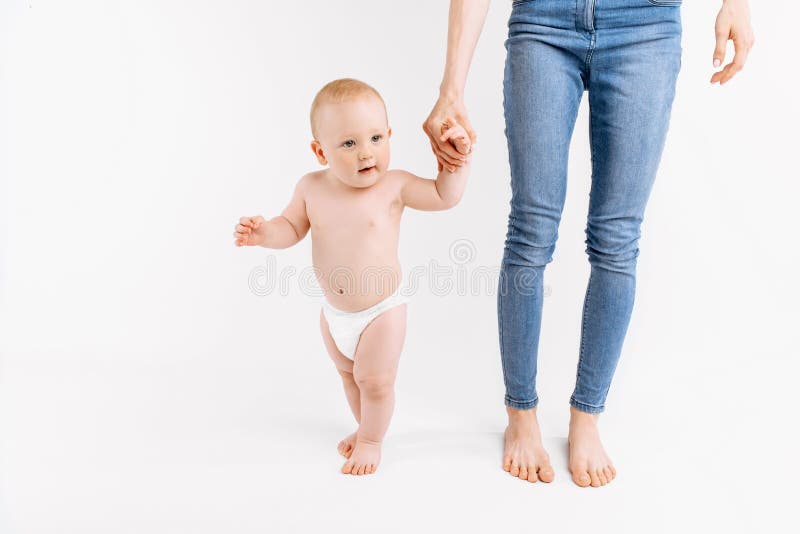 Kleines Kind lernt, mithilfe der Mutter auf einem weißen Hintergrund zu gehen. stockbild