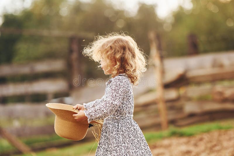 Kleines Mädchen in blauer Kleidung ist im Sommer draußen auf dem Bauernhof lizenzfreies stockbild