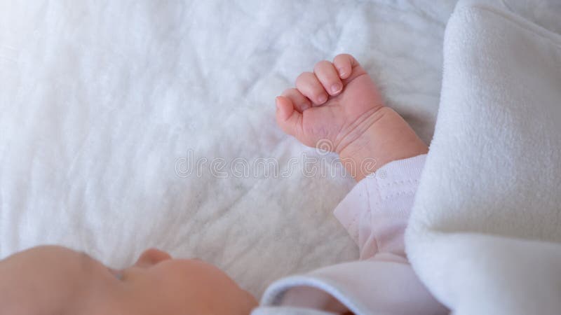 Kleines, kleines Mädchen, das ein kleines Kind mit der Hand in der Kinderstube auf einem weißen Baumwollbett hat lizenzfreie stockfotografie
