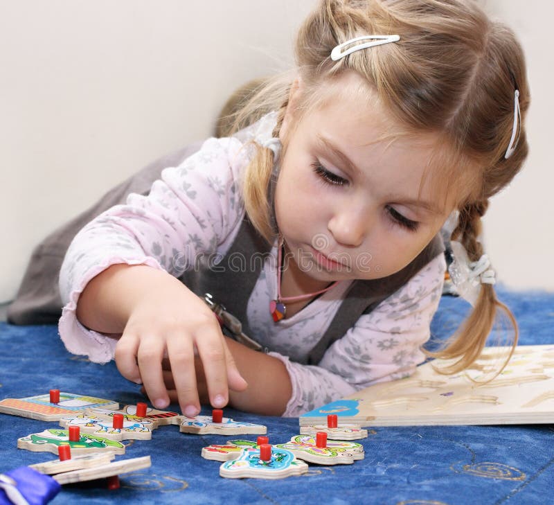 Kleines Mädchen, das hölzerne Puzzlespiele spielt stockfotos Kleines Mädchen, das hölzerne Puzzlespiele spielt stockfotos