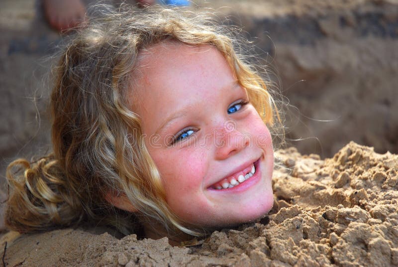 Kleines Mädchen, das im Sand spielt stockbild Kleines Mädchen, das im Sand spielt stockbild