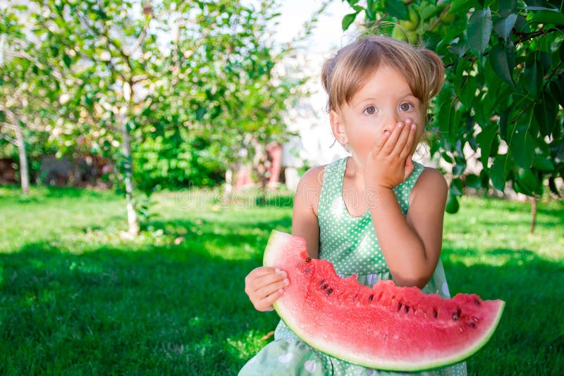 Kleines Mädchen im grünen Kleid, barfuß stehend im Park mit großer Scheibenwassermelone stockfotos Kleines Mädchen im grünen Kleid, barfuß stehend im Park mit großer Scheibenwassermelone stockfotos