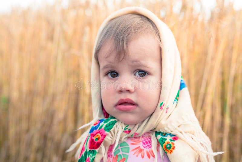 Little girl in national scarf stands in the middle of the field. Little girl in national scarf stands in the middle of the field.