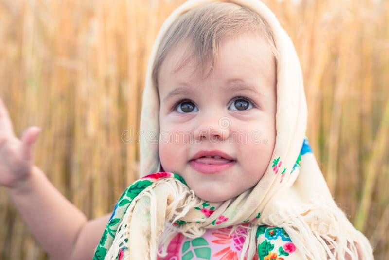 Little girl in national scarf stands in the middle of the field. Little girl in national scarf stands in the middle of the field.