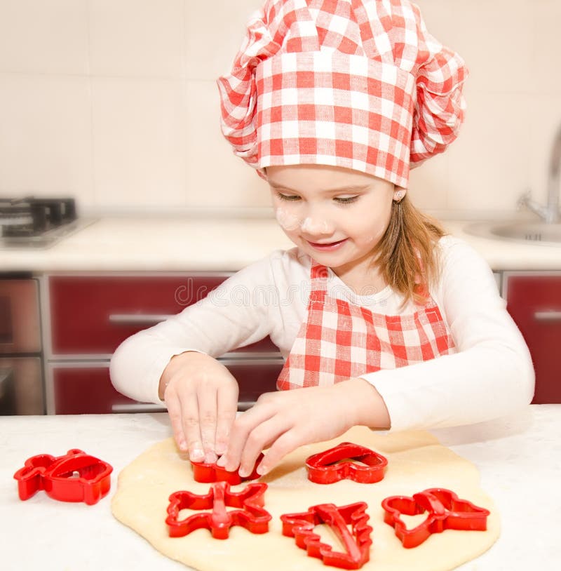Kleines Mädchen schneidet Teig mit Form für Plätzchen lizenzfreies stockfoto Kleines Mädchen schneidet Teig mit Form für Plätzchen lizenzfreies stockfoto