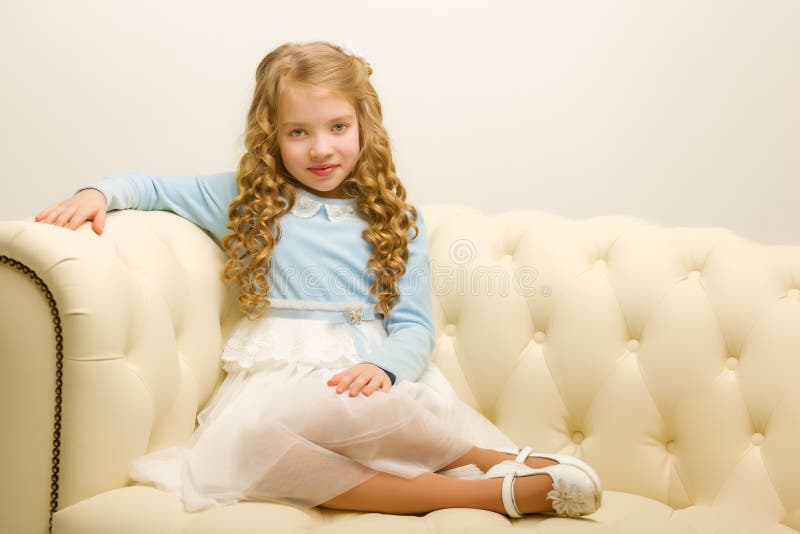 Kleines Mädchen sitzt auf dem Sofa lizenzfreies stockfoto