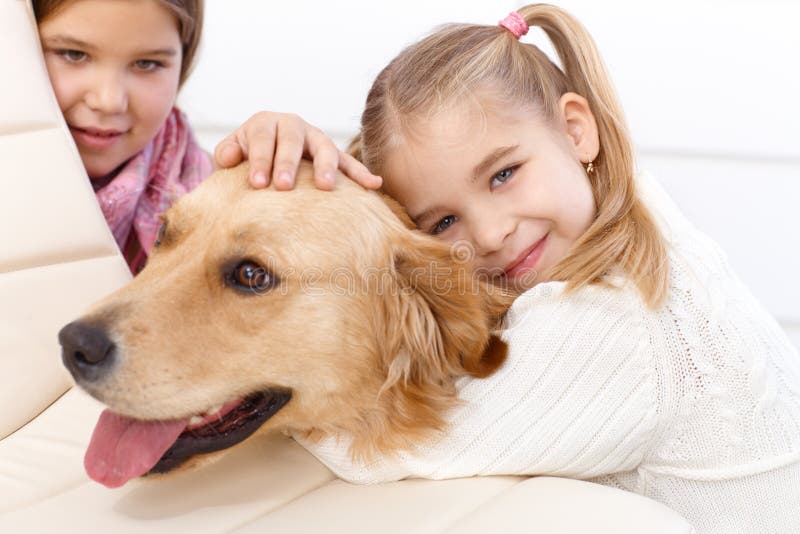 Kleines Mädchen, welches Haustierhundedas lächeln umarmt stockbilder