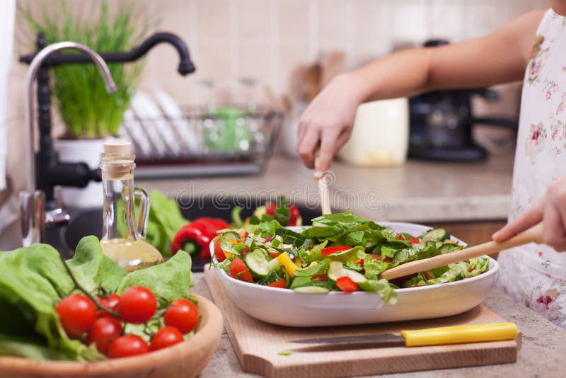 Kleines Mädchen übergibt das Mischen des gehackten Gemüses in einen Salat, SH lizenzfreies stockfoto