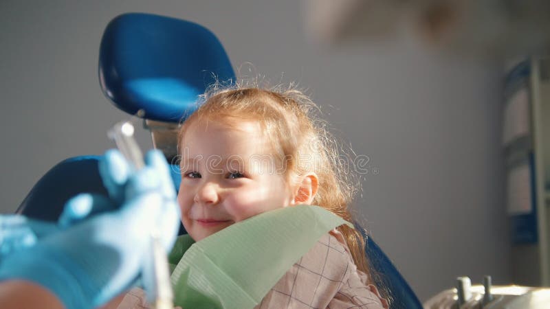 Kleines nettes Mädchen im Zahnarzt ` s Büro möchte nicht behandelt sein und widerstände und schließt ihrem Mund mit ihren Händen