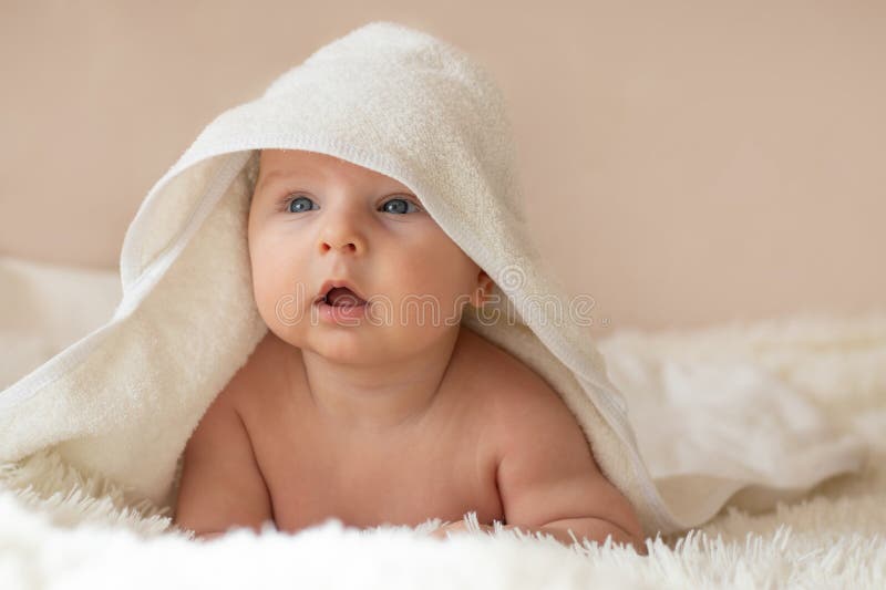 Kleinkind, das nach dem Bad oder Dusche im Schlafzimmer in weißes Handtuch verpackt ist. Abschlussportrait. Babybetreuungskonzept. selektiver Fokus