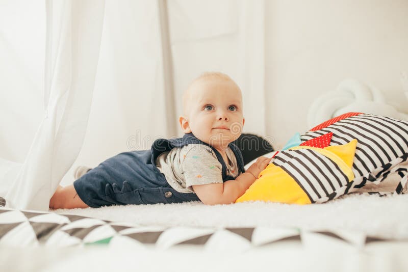 Kleinkind liegt auf Bett nahe bei bunten Kissen lizenzfreie stockfotos Kleinkind liegt auf Bett nahe bei bunten Kissen lizenzfreie stockfotos