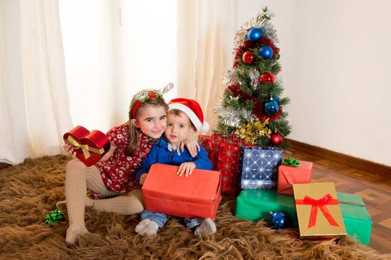 Kleinkinder auf Wolldeckenöffnung Weihnachtsgeschenken stockbilder Kleinkinder auf Wolldeckenöffnung Weihnachtsgeschenken stockbilder