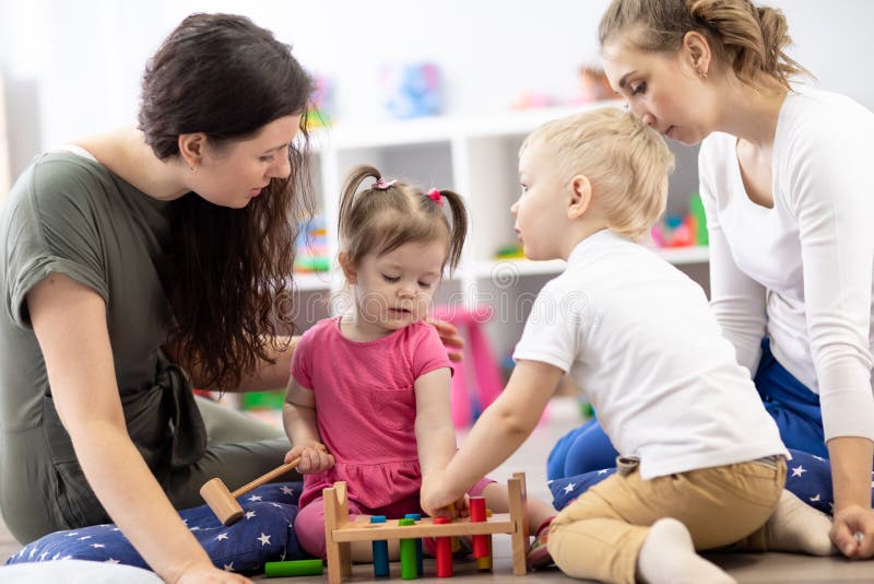 Kleinkinder und Mütter, die mit farbenfrohen Spielzeug im Kinderzimmer spielen