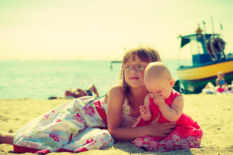 Kleinkindmädchen, das kleine Schwester auf Strand umarmt lizenzfreies stockbild Kleinkindmädchen, das kleine Schwester auf Strand umarmt lizenzfreies stockbild