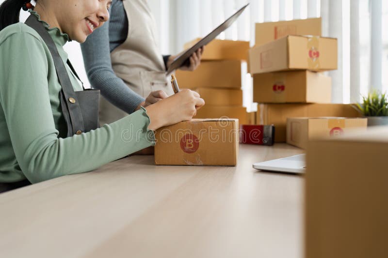 Kleinunternehmer, die Pakete für den Versand in modernem Büroumfeld vorbereiten stockfoto