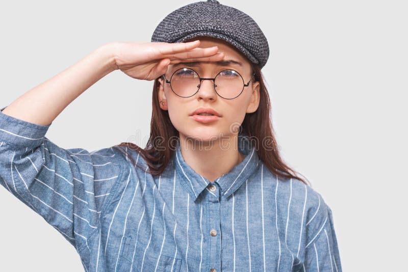 Klem studio portret van Kaukasische jonge vrouw die zich poselt voor reclame met een blauw hemd, grijze dop en ronde, doorzichtig royalty-vrije stock foto's Klem studio portret van Kaukasische jonge vrouw die zich poselt voor reclame met een blauw hemd, grijze dop en ronde, doorzichtig royalty-vrije stock foto's