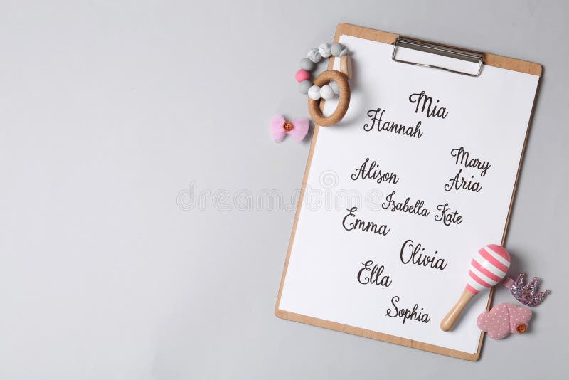 Clipboard with different baby names and toys on grey background. Space for text. Clipboard with different baby names and toys on grey background. Space for text