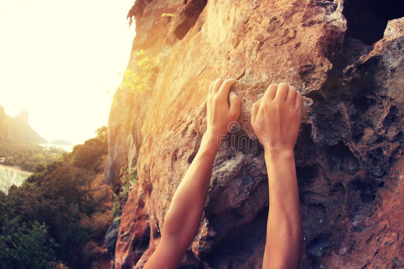 Young woman rock climber hands climbing at seaside mountain cliff rock. Young woman rock climber hands climbing at seaside mountain cliff rock