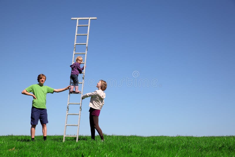 Young child climbs a ladder on a meadow with blue sky. Young child climbs a ladder on a meadow with blue sky