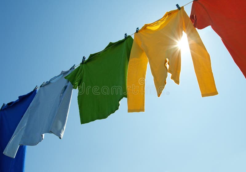 Kleurrijke kleren op een wasserijlijn en zon het glanzen