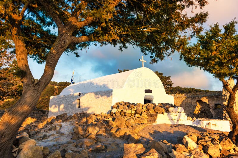 Kleurrijke mening van Griekse orthodoxe kerk die op ruïnes van Monolithos-kasteel tijdens zonsondergang Rhodos, Griekenland wordt stock fotografie Kleurrijke mening van Griekse orthodoxe kerk die op ruïnes van Monolithos-kasteel tijdens zonsondergang Rhodos, Griekenland wordt stock fotografie