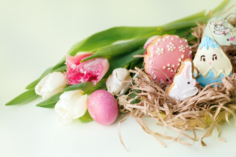Kleurrijke Pasen-koekjes met het berijpen van suikerglazuurdecor, geschilderde kleurrijke eieren en tulpen op lichte lijst Het co royalty-vrije stock afbeelding Kleurrijke Pasen-koekjes met het berijpen van suikerglazuurdecor, geschilderde kleurrijke eieren en tulpen op lichte lijst Het co royalty-vrije stock afbeelding